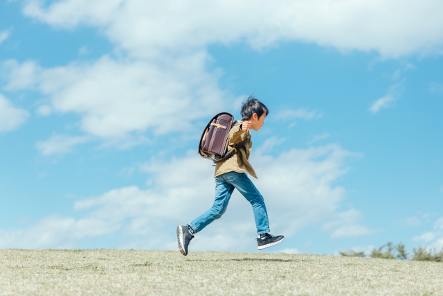男の子が、青空の下元気に登校している写真
