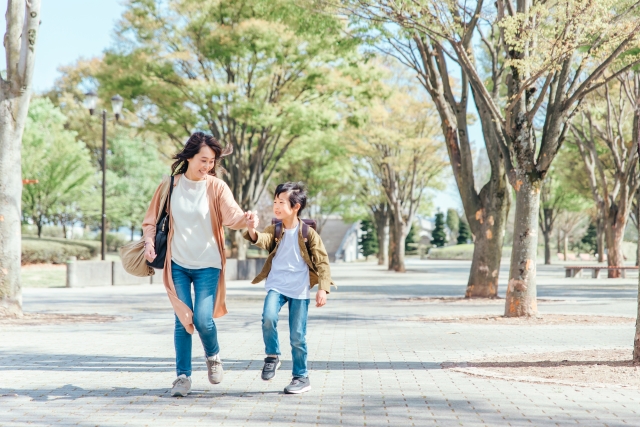 小学生と母親が元気に小学校に登校している写真